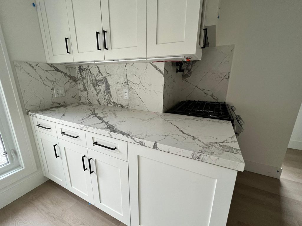 Quartz countertop and full-height backsplash with bold black veining in a Calgary kitchen