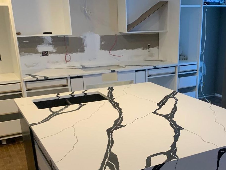 Custom quartz kitchen island with bold black veining during installation in Calgary